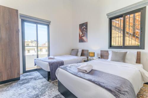 Residence 4 - Comfy Apts & Balconies in Mar Mikhael في Al Mudawwar: غرفة نوم بها سريرين ونافذة