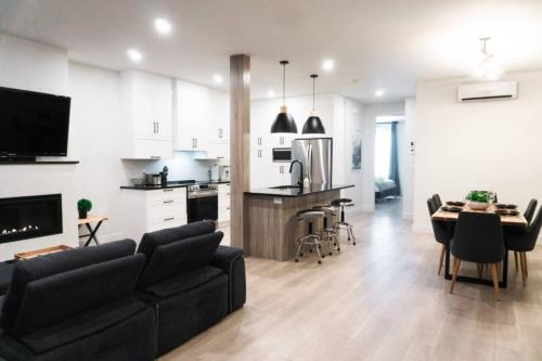 a living room with a black couch and a kitchen at Lynx spa detente Orford in Magog-Orford
