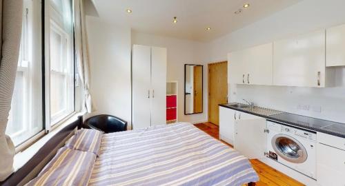 a small room with a bed and a washing machine at Modern Studio, 1st floor, King Street Views in Nottingham