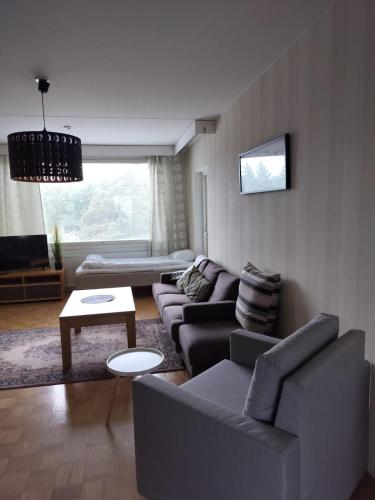 een woonkamer met een bank en een tafel bij Kotimaailma - Valoisa ja tilava neliö in Turku