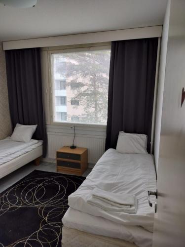 een kleine slaapkamer met twee bedden en een raam bij Kotimaailma - Valoisa ja tilava neliö in Turku