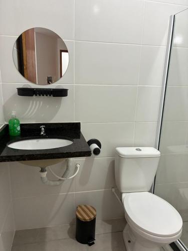 a bathroom with a toilet and a sink and a mirror at Apartamento do Peró in Cabo Frio