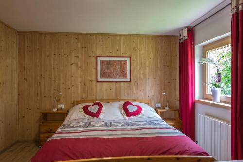 1 dormitorio con 1 cama con 2 almohadas cardiacas en BAITA CUCOL: APPARTAMENTO CON GIARDINO PRIVATO, en Cogolo