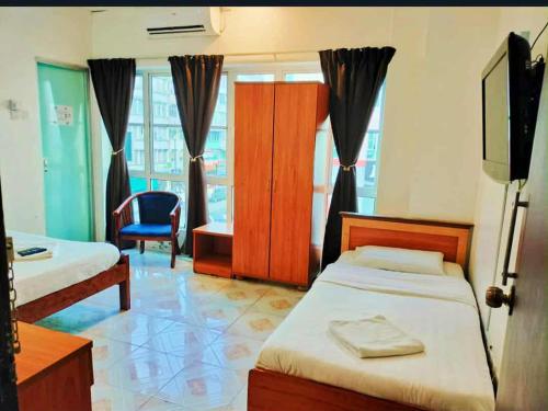 a bedroom with two beds and a chair and a television at Hotel Western in Sandakan