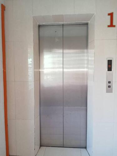 a metal elevator in a white tiled wall at Hotel Western in Sandakan