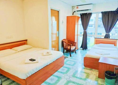 a hotel room with two beds and a chair at Hotel Western in Sandakan