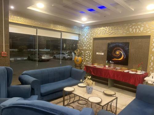 a living room with blue couches and a table at فندق اجنحة السمو إن in Aḩad al Masāriḩah