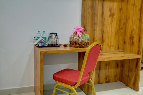 a wooden desk with a red chair next to a table at Fly Inn Bangalore Airport in Muthugadahalli