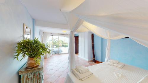 a bedroom with a white canopy bed with a potted plant at Villa Ambiance in Kyrenia
