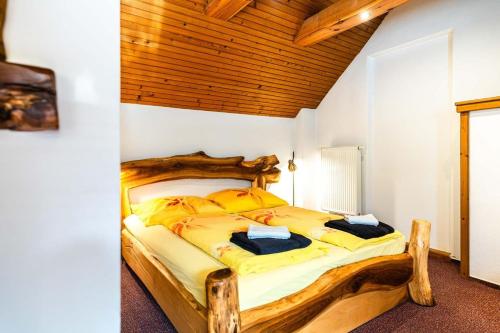 a bedroom with a large wooden bed with yellow sheets at Apartman Kamzik - 2 in Veľká Lomnica