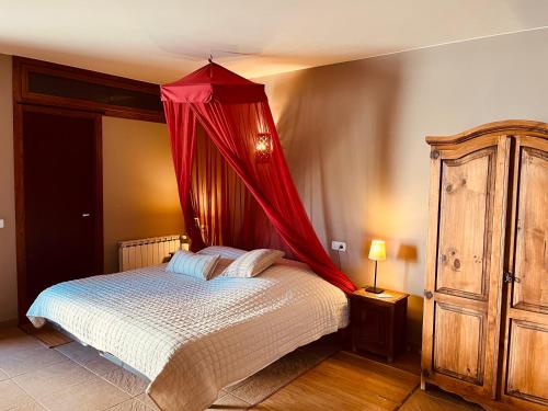 a bedroom with a bed with a red canopy at B&B El Ranxo in Franciach