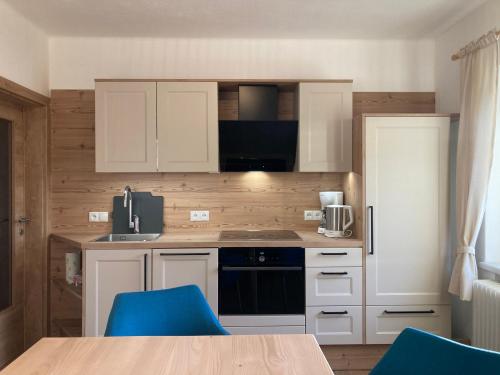 a kitchen with white cabinets and blue chairs at Haus Werner, Ferienwohnung mit Sommercard in Ramsau am Dachstein