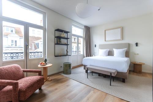 a bedroom with a white bed and a chair at Le Catherine by Sweett in Brussels
