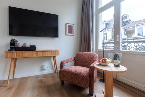 a living room with a chair and a table and a window at Le Catherine by Sweett in Brussels
