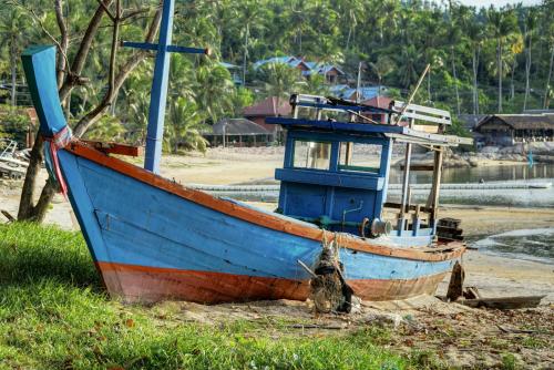 a blue and orange boat sitting on the beach at Gila's Garden in Lamai