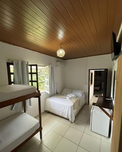 a bedroom with two beds and a wooden ceiling at Pousada Arraial da Poesia in Arraial d'Ajuda