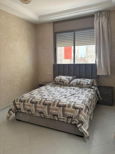 a bedroom with a bed with a comforter and a window at Ber appartement in Mirleft