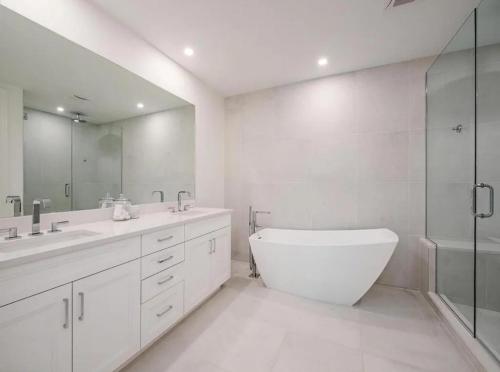a white bathroom with a tub and a sink and a shower at Stylish Downtown Naples Retreat in Naples