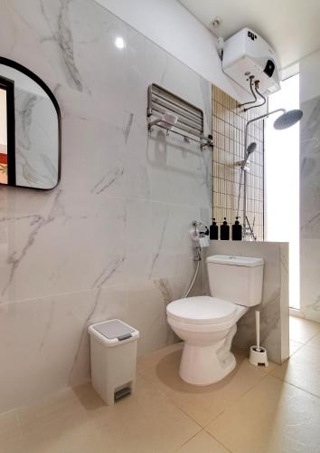 a white bathroom with a toilet and a mirror at Trevista With Private Pool in Curug 1