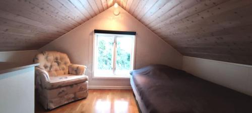 Stay central & close to the sea in Henån SE09155 في Näset: غرفة بسرير وكرسي في العلية