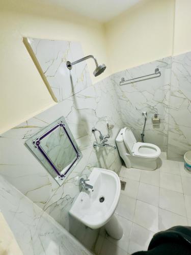 um banheiro branco com uma pia e um vaso sanitário em Pokhara hotel Pvt Ltd Ktm em Catmandu