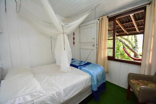 a bedroom with a bed with a mosquito net at Hostel do Morro in Florianópolis