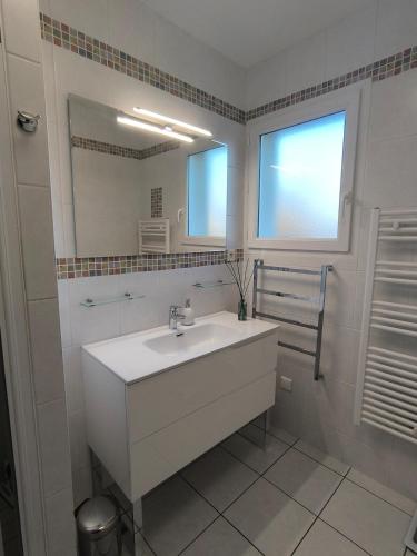 a white bathroom with a sink and a mirror at La Parenthèse colorée - spacieux - 12mn du Parc in Châteaumur