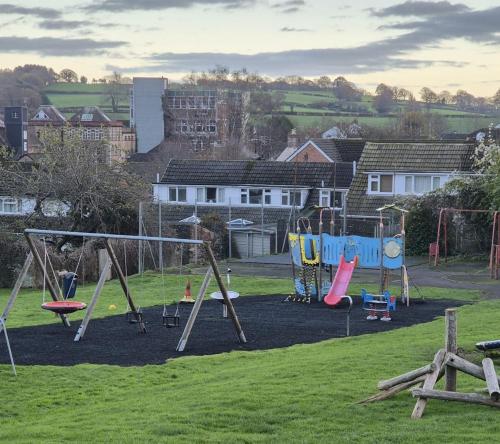 a playground in a grassy field with swings at The Ferns in Mitcheldean