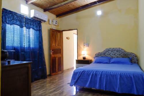 a bedroom with a bed with blue sheets and a window at Ulises House in Luque