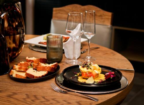 een houten tafel met een bord eten en wijnglazen bij Peggie's Boutique Hotel in Koning Willemstad