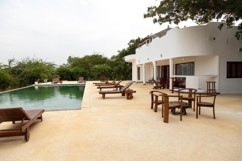 a patio with tables and benches next to a pool at Résidence Farafina in Somone