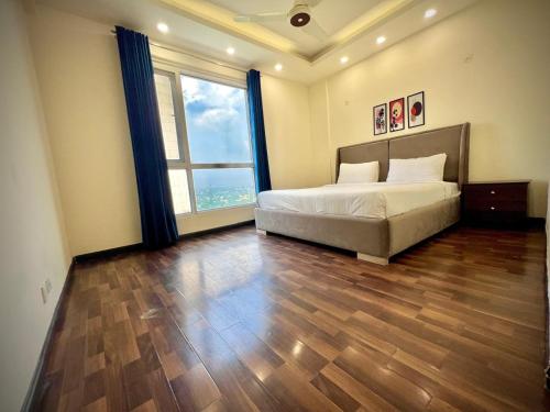 拉合尔Gold Crest Prime Heights Executive Apartments-DHA Lahore的一间卧室，里面有一张床和一扇大窗户。