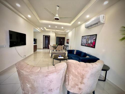 拉合尔Gold Crest Prime Heights Executive Apartments-DHA Lahore的客厅里有一张蓝色的沙发和椅子
