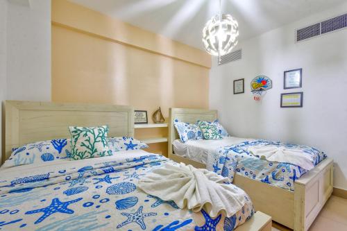 a bedroom with two beds and a chandelier at Las Olas, Juan Dolio 2bed2bath Condo in Guayacanes