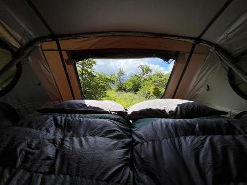a tent with a bed in it with a window at Yellow Plum Camp Pehoé in Torres del Paine
