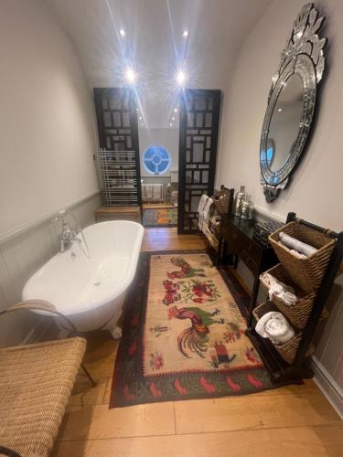 un bagno con vasca, lavandino e specchio di Castellmai a Caernarfon