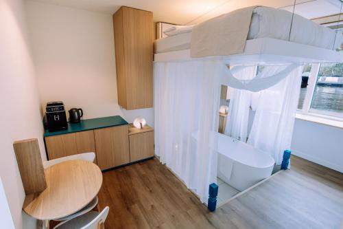 Schlafzimmer mit einem Bett, einem Tisch und einer Badewanne in der Unterkunft The Amsterdam Houseboat Family - de Jordaan Brand New Houseboat! in Amsterdam