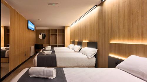 een hotelkamer met drie bedden en een televisie bij Hotel Catanies in Pas de la Casa