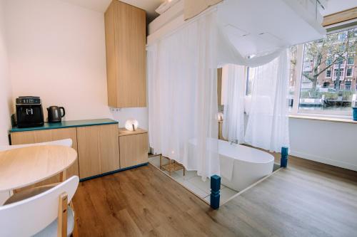 ein Bad mit einer Badewanne, einem Tisch und einem Fenster in der Unterkunft The Amsterdam Houseboat Family - de Jordaan Brand New Houseboat! in Amsterdam