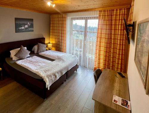 a bedroom with a bed and a large window at Hotel-Gasthof Lammersdorf in Millstatt