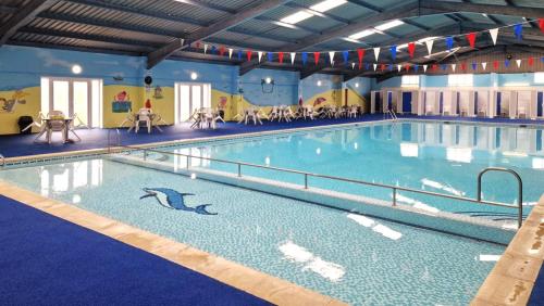 a swimming pool with a dolphin in the water at Modern Airy Chalets on popular California Sands Holiday Park - short walk to beach, Nr Norfolk Broads & Great Yarmouth in Scratby