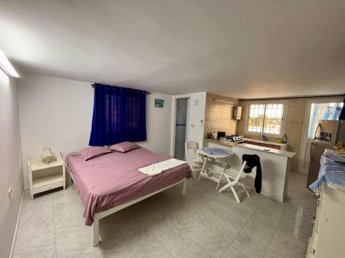 a bedroom with a bed and a table and a kitchen at Charmant studio avec vue sur mer in Nabeul