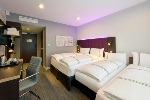 a hotel room with two beds and a desk at Premier Inn Stuttgart Zuffenhausen in Stuttgart