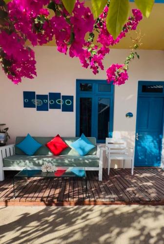 Nautical Nook Maldives في Kendhoo: أريكة تجلس تحت شجرة بها أزهار وردية