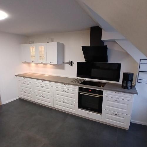 a kitchen with white cabinets and a black microwave at Eksklusiv stort boende Suite 1 in Frederikshavn