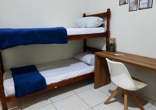 a room with two bunk beds and a desk and a chair at Pousada Villa in Piquete