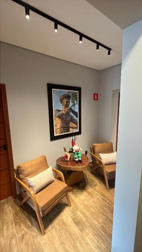 una sala d'attesa con sedie e tavolo e un quadro di Pousada Grão & Vinha a Espirito Santo Do Pinhal