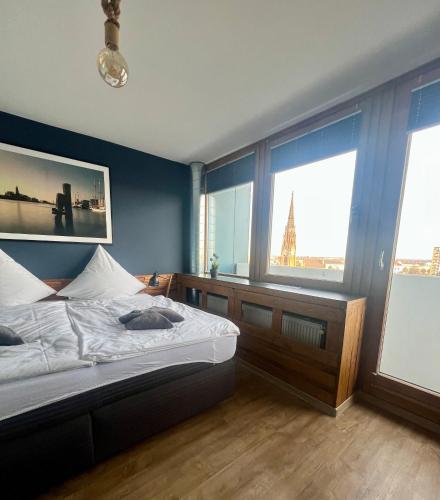 a bedroom with a bed and two large windows at COAST HOUSE Havenquartier in Bremerhaven
