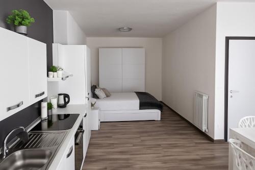 a small white room with a bed and a kitchen at Il Giardino di Lilly in Porlezza