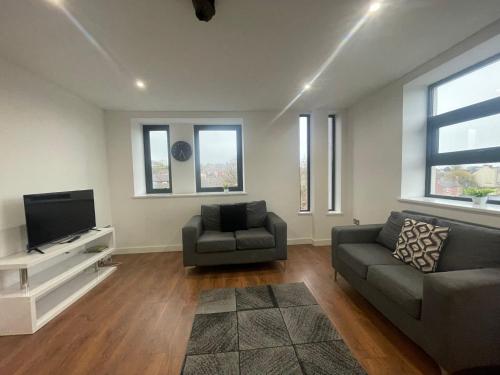 een woonkamer met een bank en een tv bij Forest Gate Nest Nottingham in Nottingham